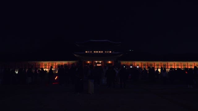 Tourists walking along the night streets of Gyeongbokgung Palace, a traditional Korean palace