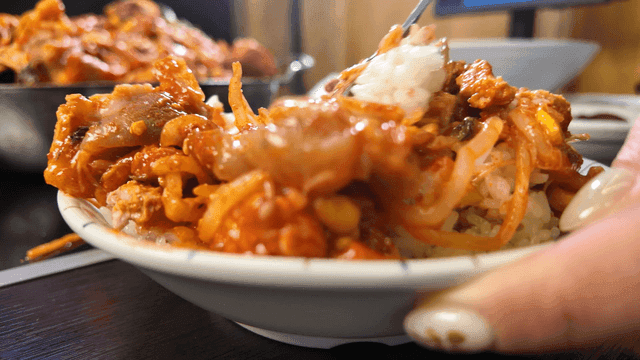 Spoon mixing spicy braised anglerfish with rice