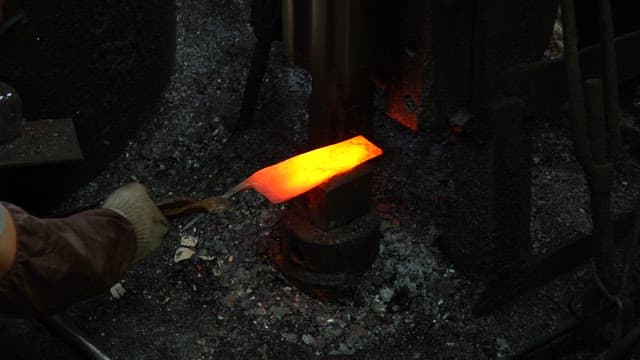 Worker forging metal in a factory