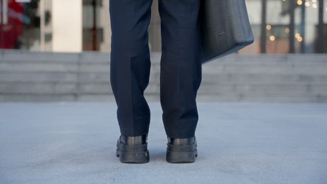 건물 입구로 걸어가는 서류가방을 든 사람