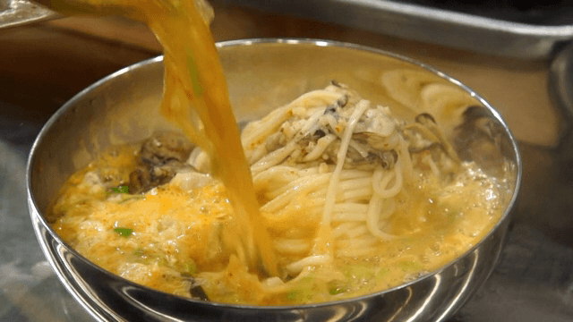 Pour broth into a bowl with oysters and noodles