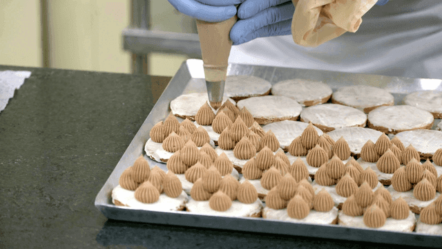 Pastry chef decorating cookies with cream