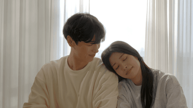 Couple sitting by window leaning on each other's shoulders