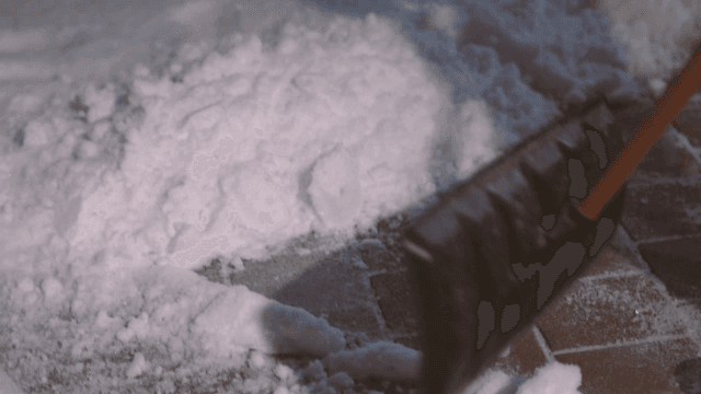 Snow shovel clearing snow from tile floor
