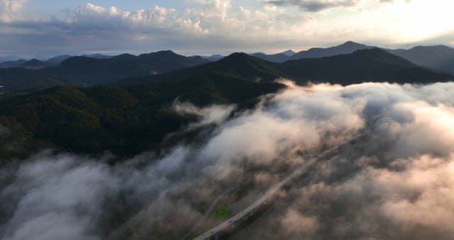 Mountains with clouds and a road