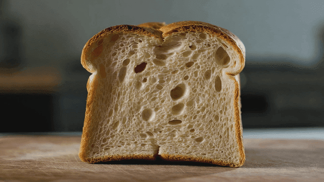 Cross-section of slice of bread on wooden cutting board