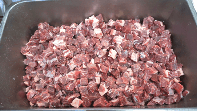 Chunks of raw meat in a metal container