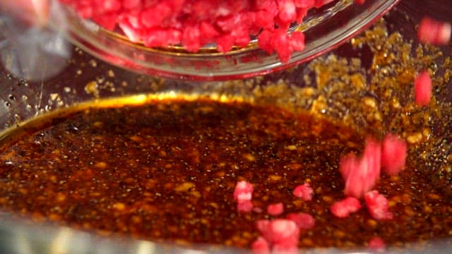 Mixing minced beef and seasoning in a metal bowl