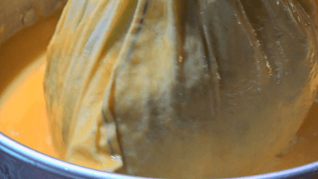 Cloth pouch lifted from orange egg mixture