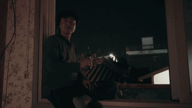 밤에 창가에 앉아 술을 마시는 남성