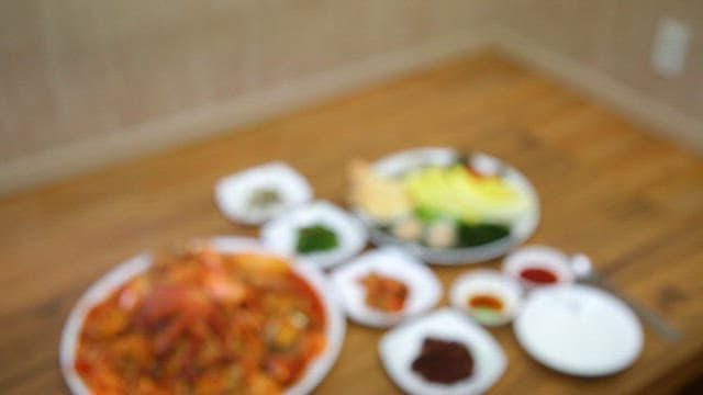 Table with sbraised spicy seafood, abalone sashimi, and various Korean side dishes