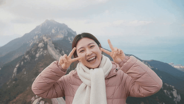 겨울 산 정상에 올라 브이하며 기뻐하는 여자