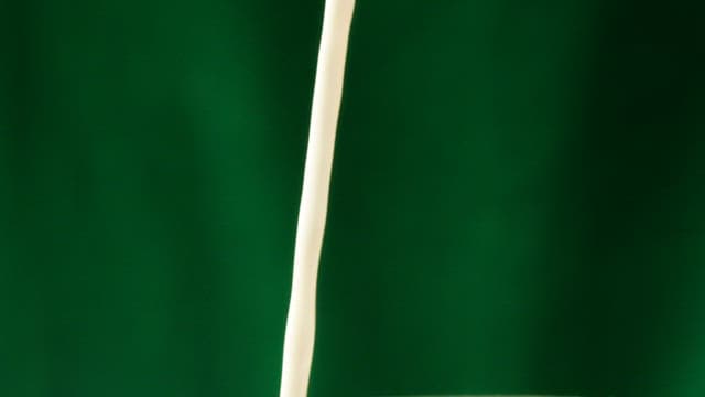 White milk and brown coffee poured against a green screen