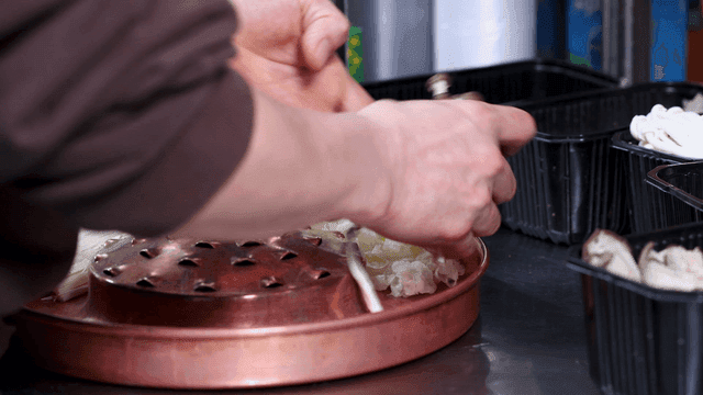 Hands preparing mushrooms for hot pot dish