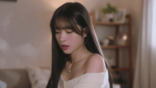 미소를 짓다 아래를 보며 한숨을 쉬는 젊은 여성