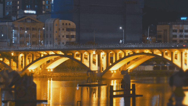 불빛이 반짝이는 야경 속 다리 도로와 강물 풍경