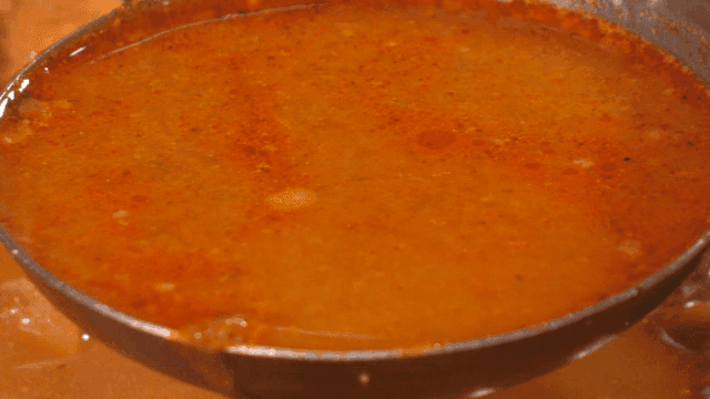 One ladle of pork backbone stew topped with sweet potato stems