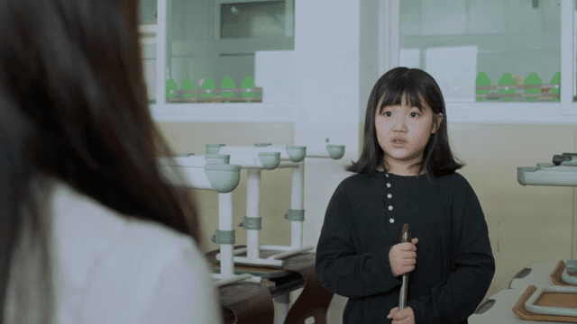 Child talking to the teacher while cleaning the classroom