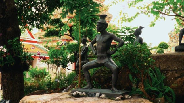 Statue in a garden inside a Thai temple with tourists