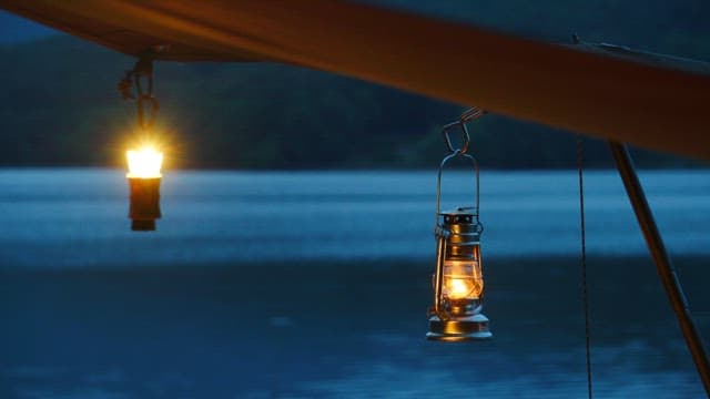 Two lanterns illuminating a serene lake at twilight