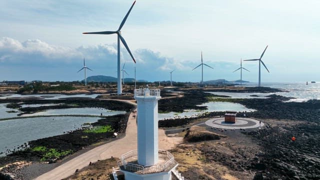 Lighthouse and wind turbines by the sea