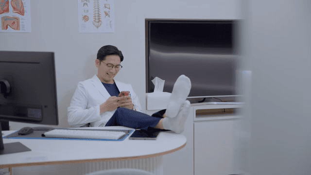 진료실에서 휴대폰을 보며 휴식을 취하는 의사