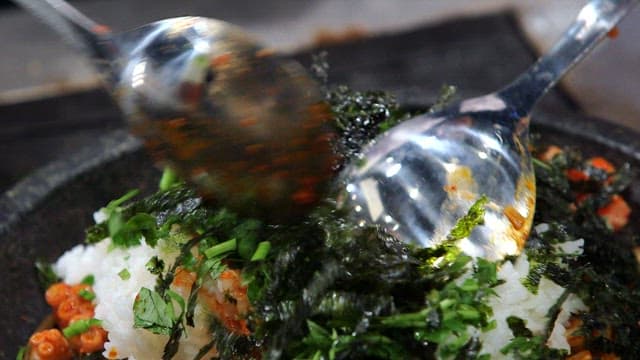 불판에서 신선한 채소와 비빔밥을 비비는 장면