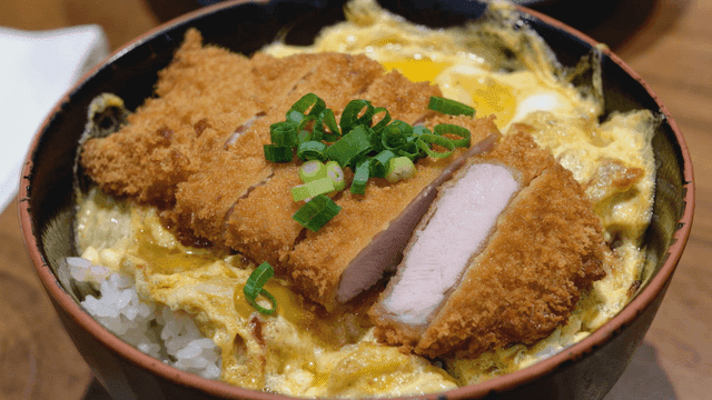 Bowl of katsudon topped with green onions