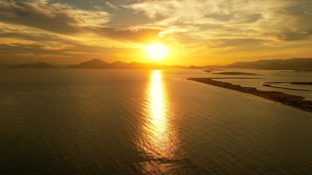 Sunset over a calm sea with distant mountains