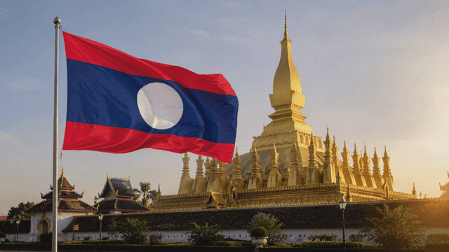 Laotian flag fluttering near golden pagoda