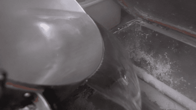 Chef pouring hot water into large mixing bowl