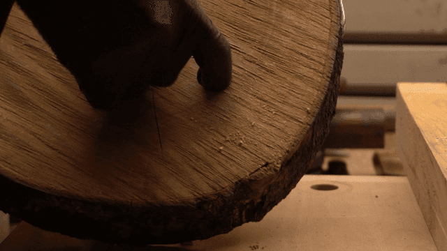 나무 통나무의 구멍을 다듬는 장갑 낀 손