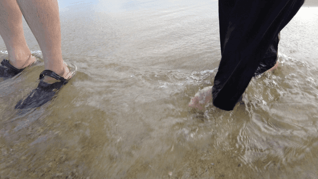 Feet in shallow water on a sandy beach