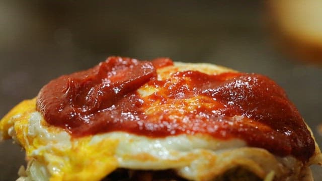 Sandwich with egg and sauce being prepared