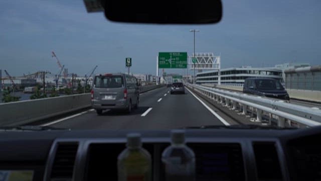 Driving on a Highway with Visible Road Signs and Buildings