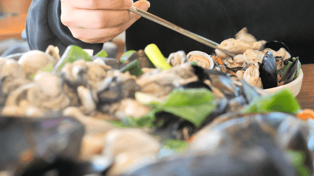 Person picking up seafood oyster kalguksu with chopsticks