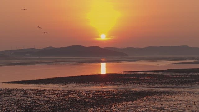 Sunset over a calm sea with distant mountains