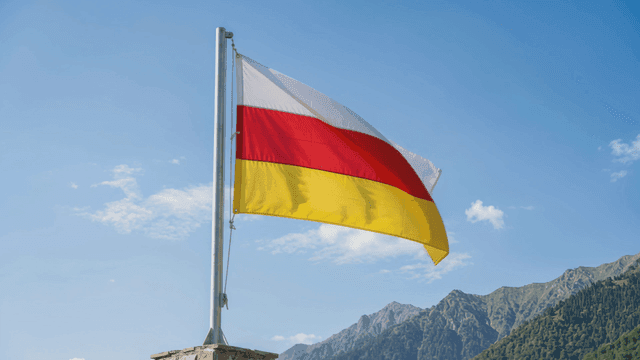 South Ossetian flag fluttering against backdrop of mountains