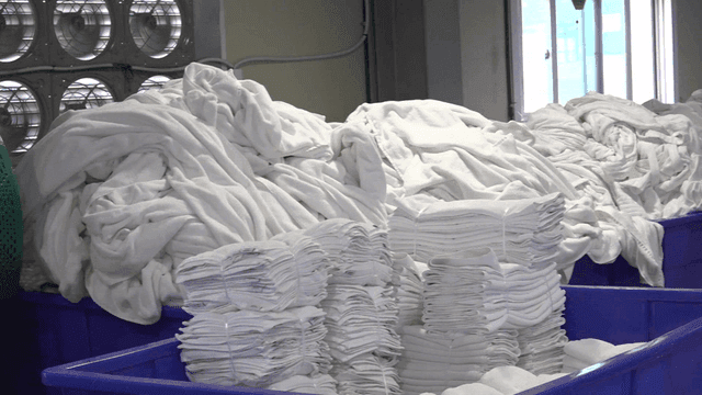 Stacks of white sheets in laundry factory facility
