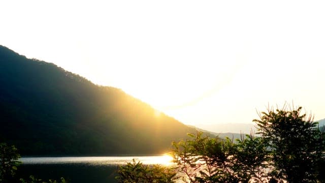 Early morning by a serene lake surrounded by mountains and forests