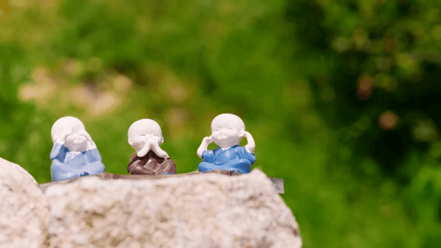 녹색 배경의 돌 위 작은 승려 조각상