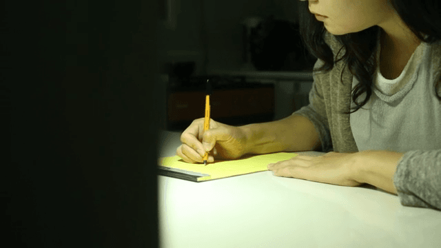 펜으로 메모장에 글을 쓰는 여성