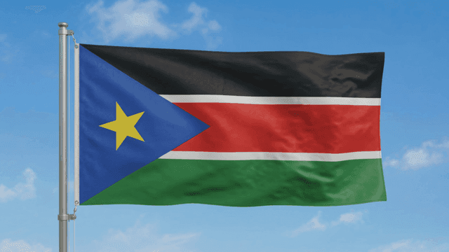 Flag of Republic of South Sudan fluttering against clear sky.