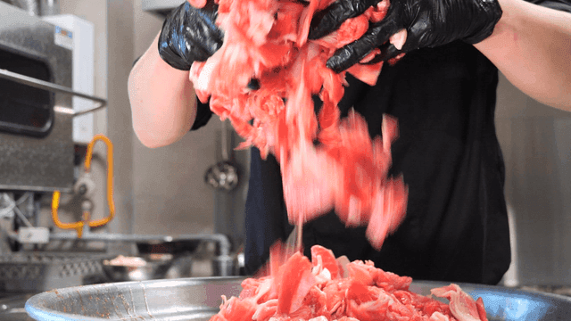 Chef separating raw meat in kitchen