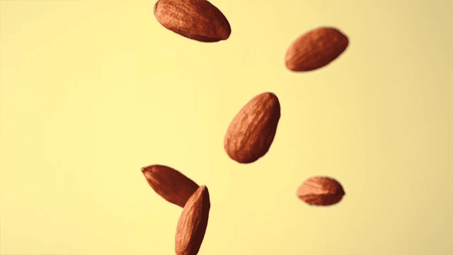 Almonds falling in slow motion against a yellow background