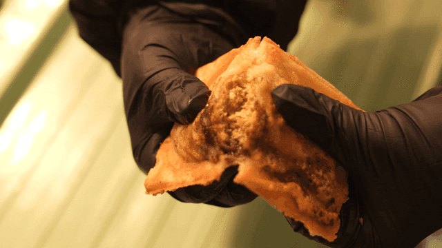 Hands smashing crispy Dubai chewy fish-shaped bread