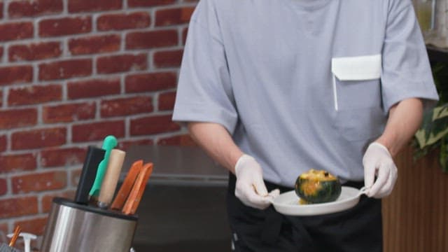 도마 위에 맛있게 조리된 단호박 그라탕을 올려놓는 장면