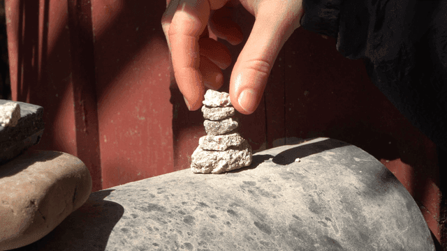 Hands stacking small stones outdoors