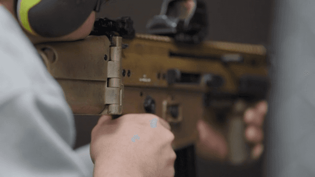 Person aiming a rifle indoors