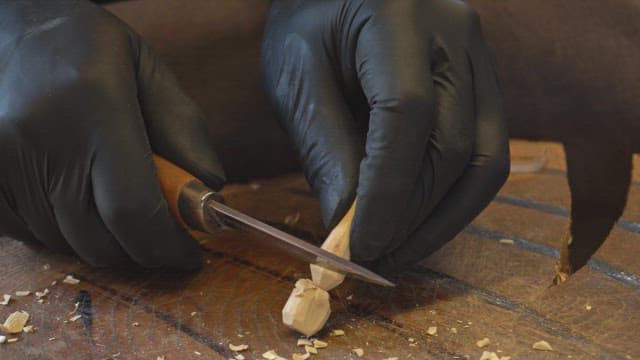 Hands carving wood with precision